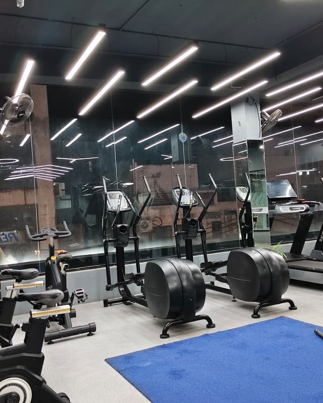 Rows of treadmills and cross trainers under strip lighting
